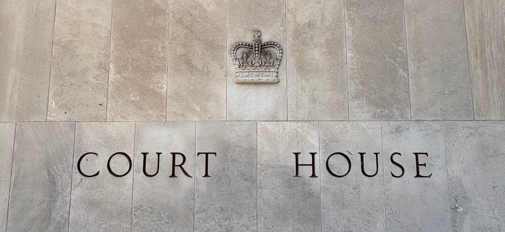 Relief of a British crown on a stone wall above the words Court House