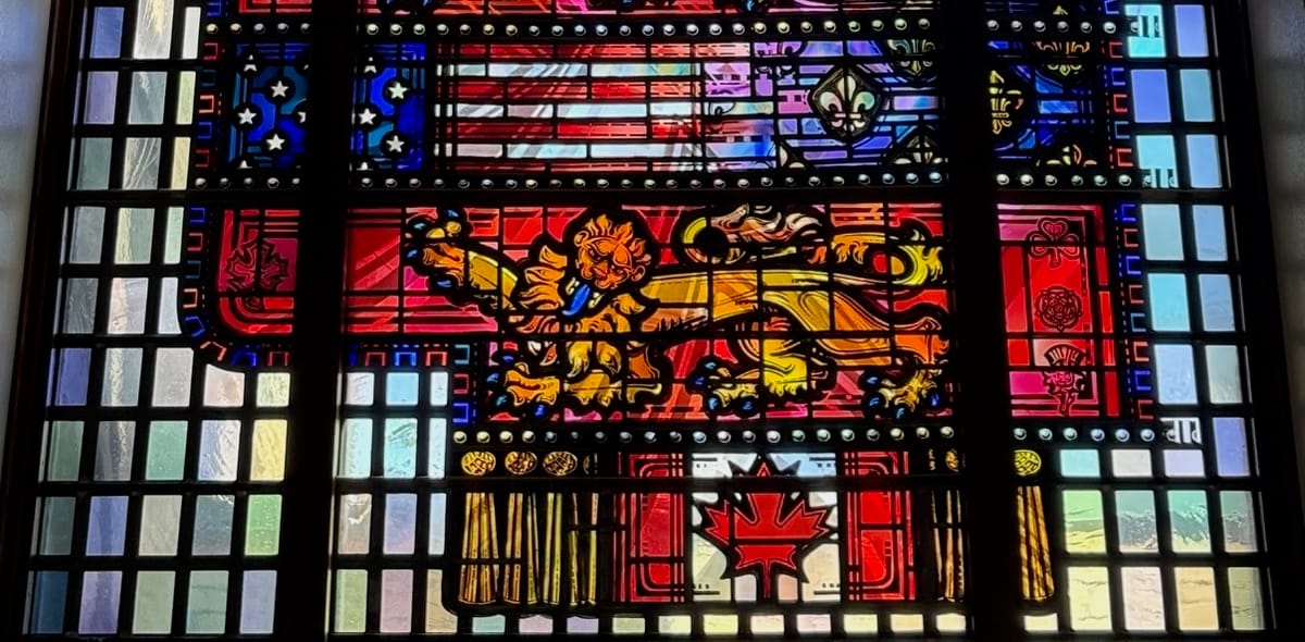Stained glass with heraldic lion, stars & stripes, fleurs de lis and the maple leaf